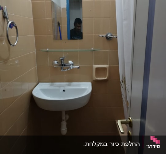 כיור עם ברז ומראה בחדר אמבטיה קטן